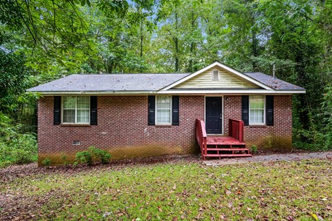 a small brick house with a red bench in front of it